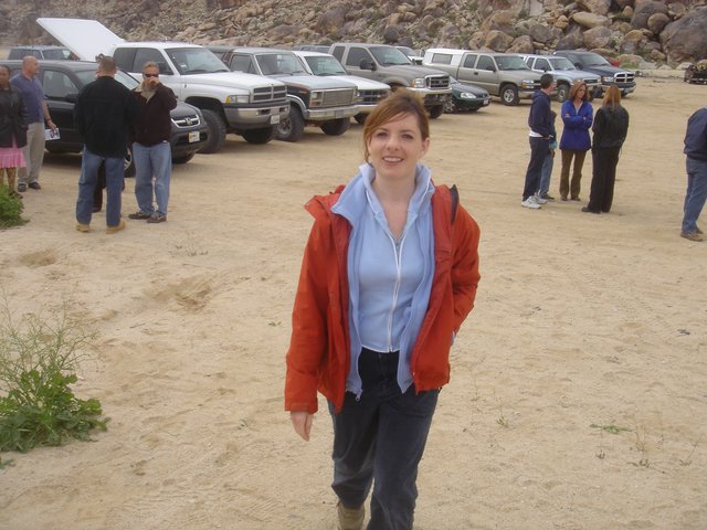 Woman Smiling in Desert Parking Area Near Rocky Hills