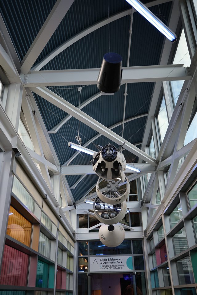 Vintage Space Telescope Suspended in Modern Observatory Atrium