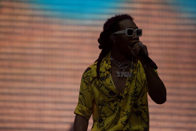 Live at Coachella Caption: A solo performer with dreadlocks and sunglasses rocks the stage, holding the microphone in one hand and energizing the excited crowd with the other.