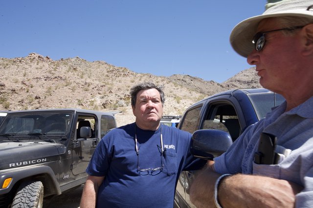 Two Men Conversing Beside Jeeps in Desert Terrain