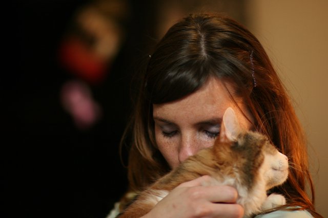 Tender Moment: Woman Embracing Ginger Kitten Lovingly