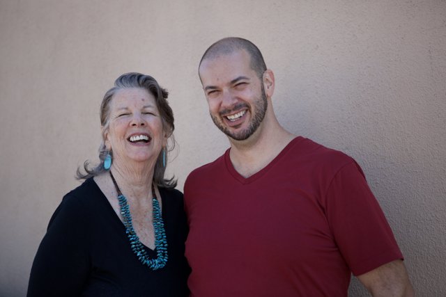 Smiling Portrait of Rhoda B and Dave B in Front of Wall