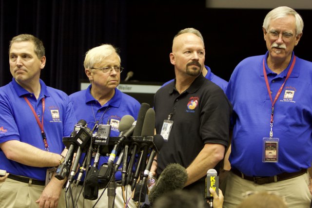 Press Conference with Four Men in Blue Shirts
