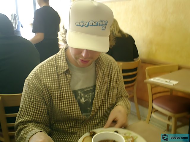 Man in a Baseball Cap Enjoying a Meal at a Downtown Cafe