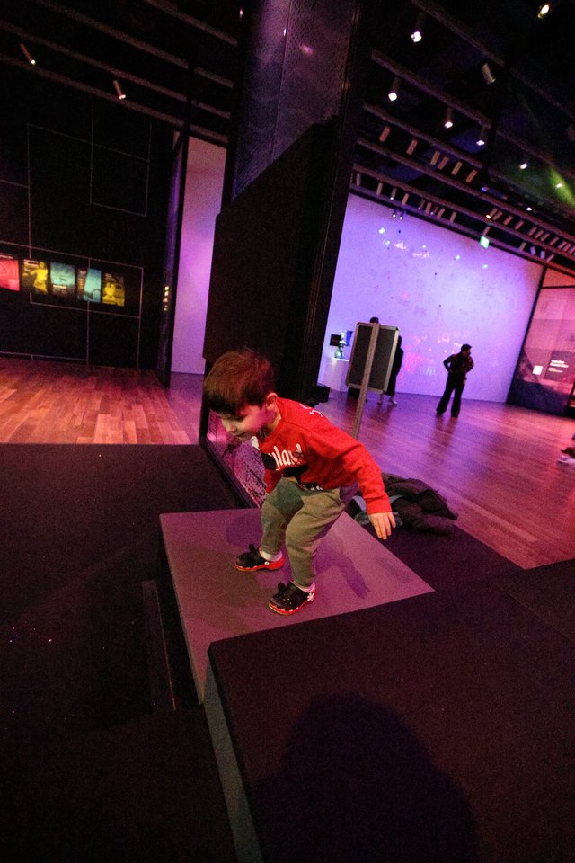 Child Exploring Interactive Museum Exhibit in Purple Light