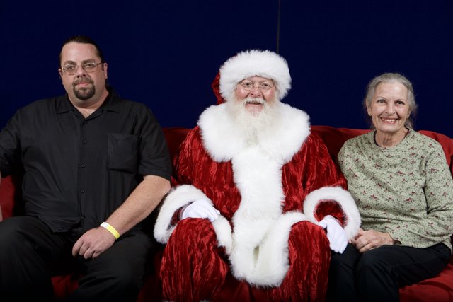 Santa Claus Joins Party Guests on Red Couch