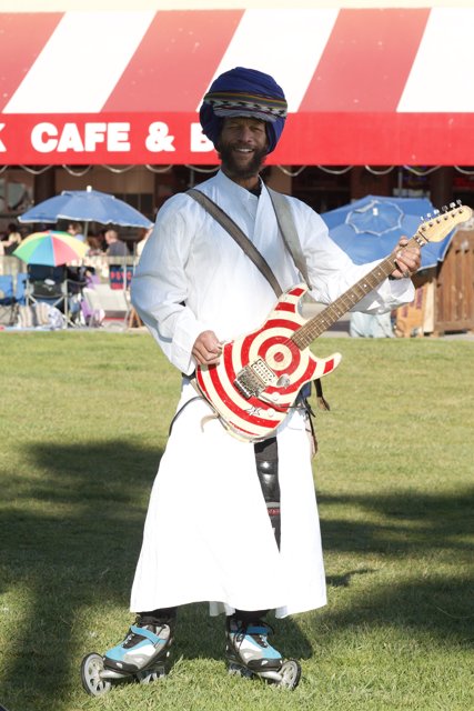 Man in White Robe Playing the Guitar Outdoors