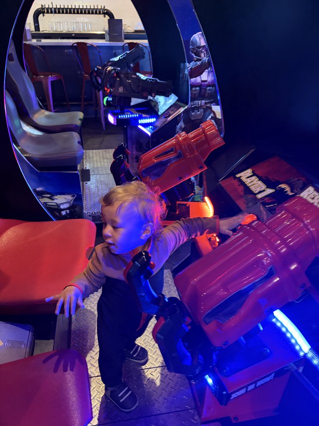 Child Playing Retro Arcade Games in Blue-Lit Gaming Pod