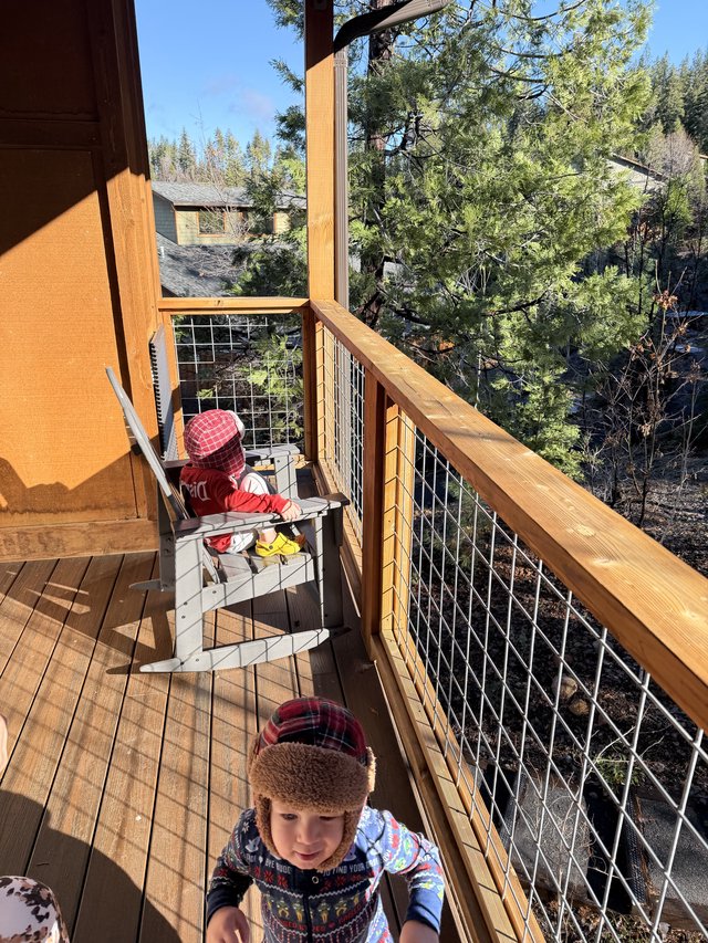 Two Young Children Enjoying a Snowy Mountain Cabin Deck