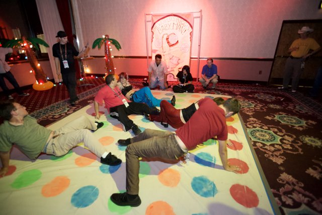 Giant game night with family and friends Caption: A group of people, including children and adults, gather together in a living room to play on a giant game. The flooring and footwear are visible, along with various clothing and accessories.