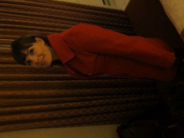 Woman in Red Coat Poses in Hotel Room