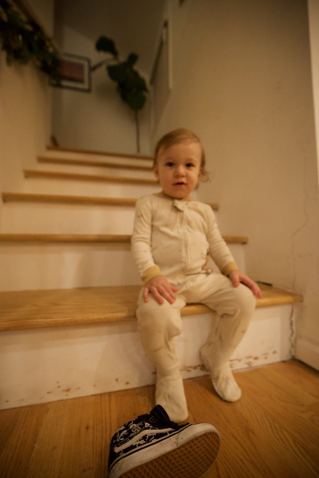 Toddler in White Pajamas Sitting on Wooden Stairs