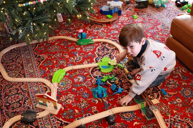 Boy Playing with Wooden Train Set on Christmas Morning