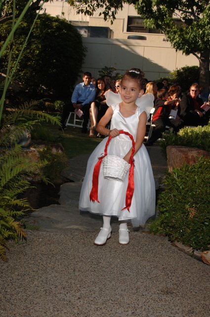 Little Girl in a White Dress Strolls Down a Garden Path