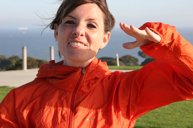 Woman in Orange Jacket Poses by the Coast