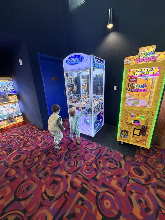 Children Playing Claw Machines at Arcade Entertainment Center