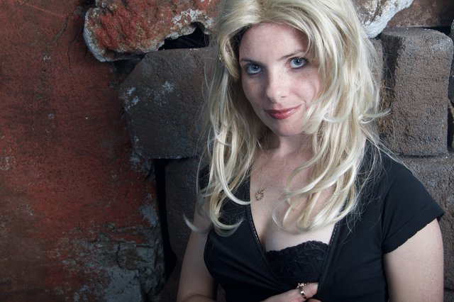 Blonde Woman Poses Against Rustic Brick Wall
