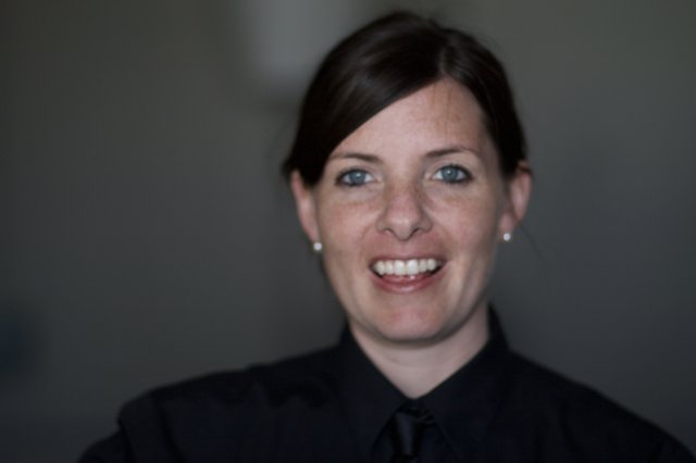 Smiling Woman in Black Against Grey Background