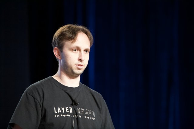 Man with Microphone in Black Shirt against Blue Background