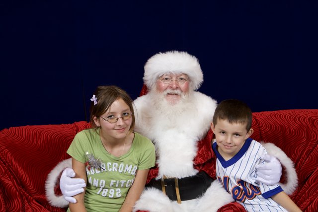 Santa Claus Spreading Holiday Cheer with Two Children on a Couch