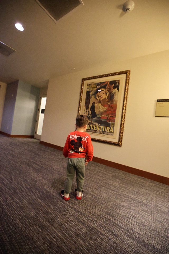 Child Admiring Vintage Film Poster in Hallway