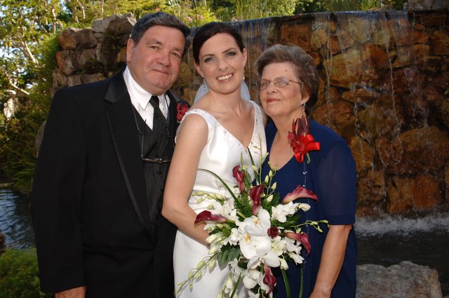 Bride Poses with Parents at Waterfall Wedding Venue