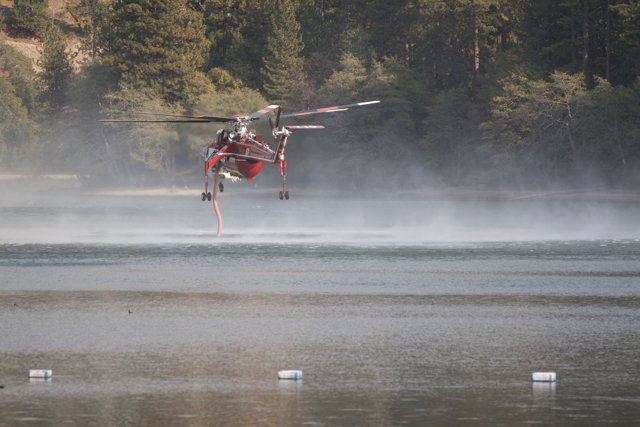 Helicopter aids in firefighting over a lake