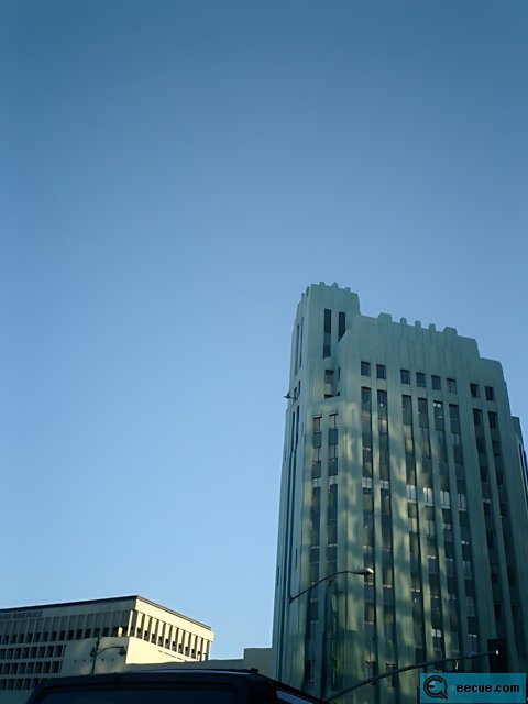 City Skyscraper Emerging Among Blue Skies