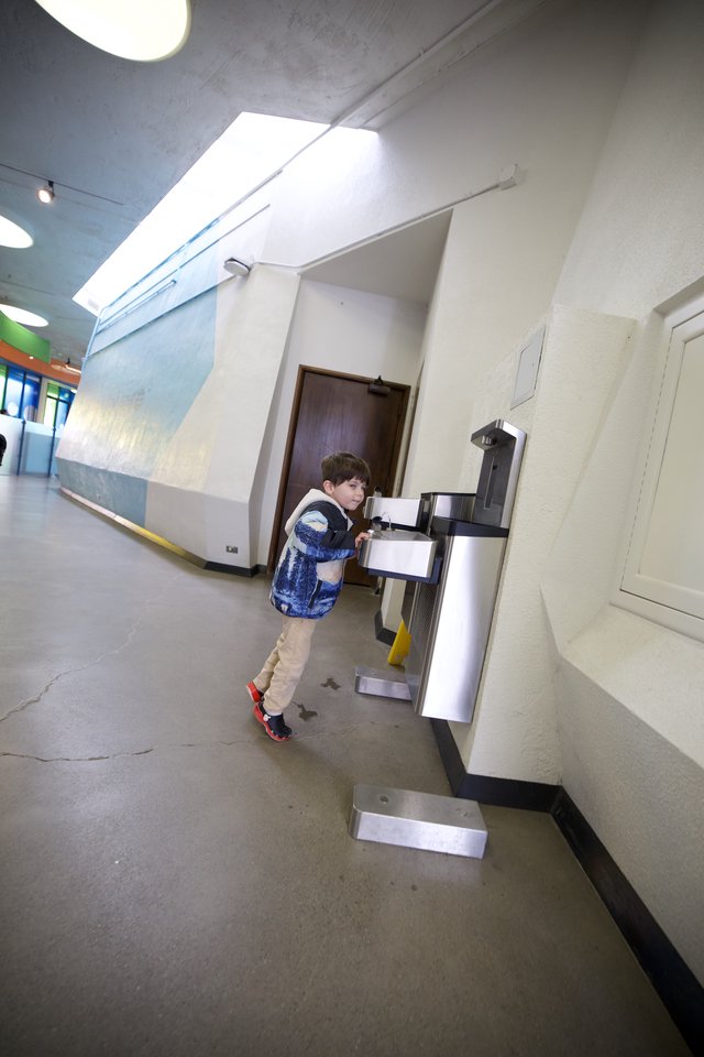 Young Student at Water Fountain in School Hallway
