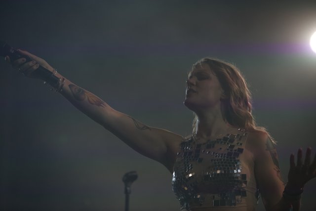 Tattooed Woman Holds Up Hand in Concert Crowd