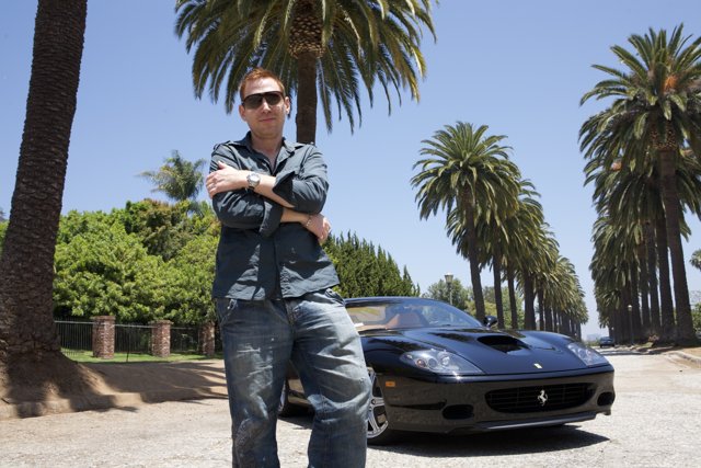 Man posing next to a luxurious Ferrari