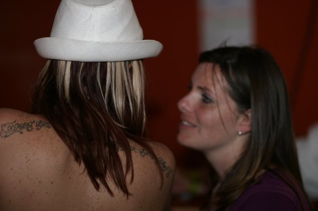 Tattooed Woman in White Fedora Shares a Moment