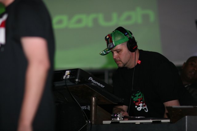 DJ Sam R Performing with Headphones and Green Cap