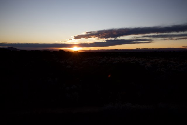 Dramatic Sunset Over Desert Landscape with Silhouetted Scrubland