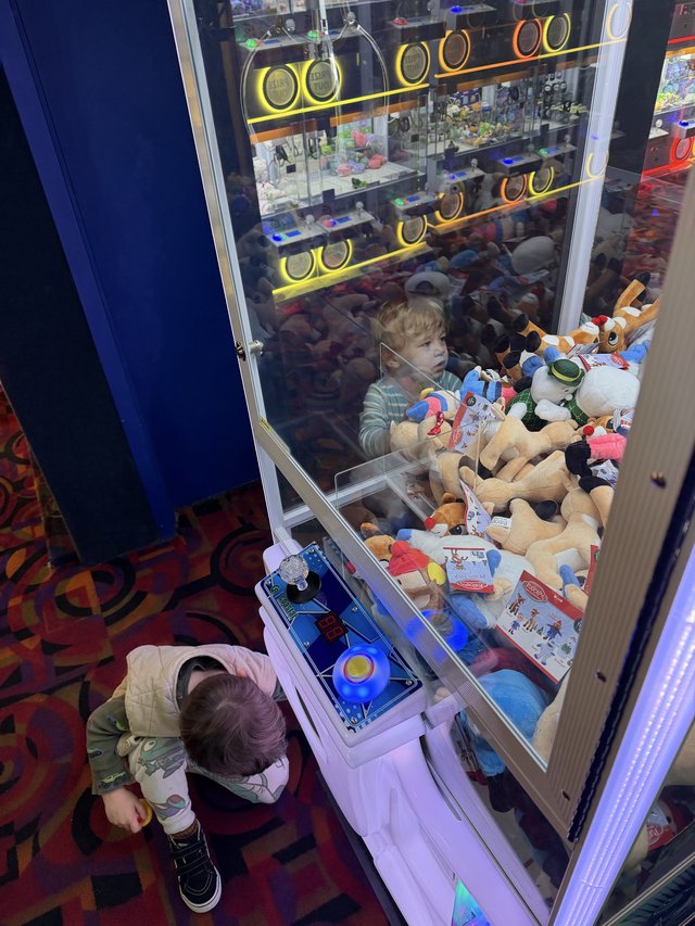 Child Playing Claw Machine Game at Arcade