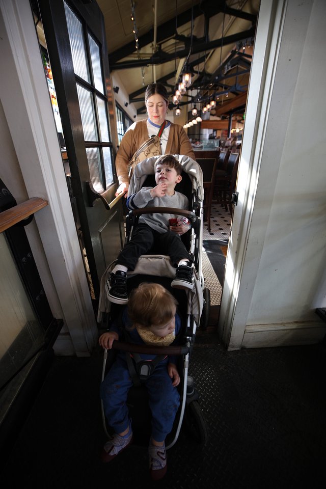 Mother with Two Children Navigating Narrow Restaurant Doorway