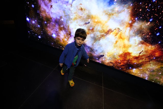 Child Exploring Cosmic Nebula Display at Space Center