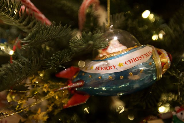 Merry Christmas Ornament on Evergreen Tree with Twinkling Lights