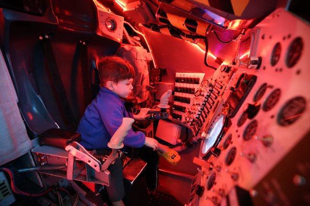 Young Visitor Explores Submarine Control Room Exhibit