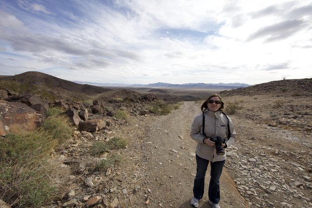 Photographer Stands on Desert Ridge Trail Overlooking Valley