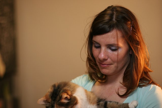 Tender Moment: Woman Cradling Calico Kitten Indoors