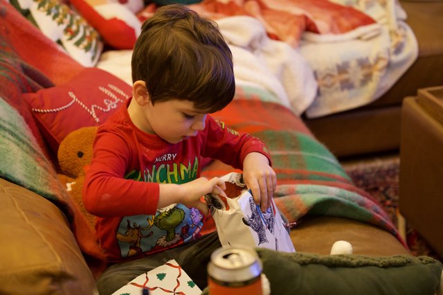 Young Child Opening Christmas Presents in Cozy Living Room