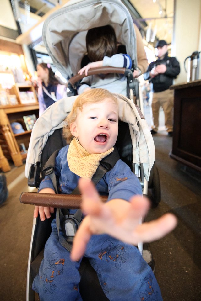 Joyful Child Reaching Out in Double Stroller