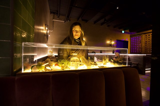 Woman Examining Illuminated Museum Display Case at Night