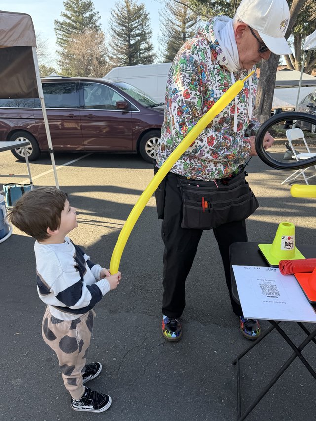 Child Receiving Yellow Balloon at Community Event