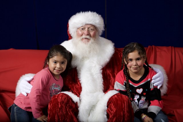 Santa Claus Visits Two Girls on Red Sofa