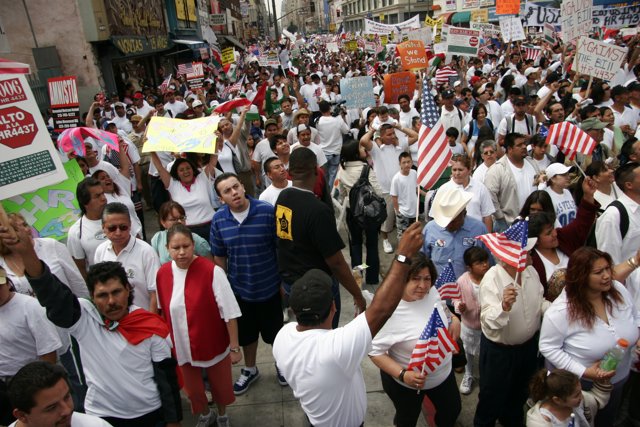 March for America Caption: Lachlan Sharp, Ivana Maria Furtado, Antônio Rogério Nogueira, Jiggy Manicad, Gouher Sultana, and Hayato Tani join a crowd of 63 people at the March for America parade, holding flags and signs for their cause.