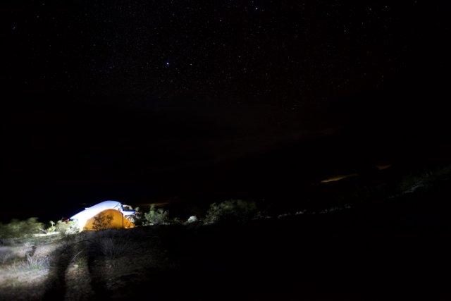 Mountain tent under the starry sky Caption: A cozy camping night under the stars, with a lit up mountain tent providing the perfect shelter for outdoor enthusiasts.