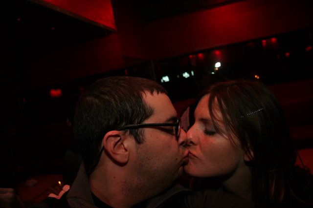 A Couple Sharing a Kiss at a Dimly Lit Bar