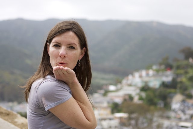 Woman Blowing a Kiss Over Hillside Town